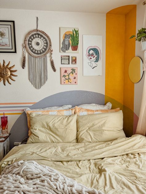 a corner of a bedroom featuring a painted headboard, gallery wall with dream catcher, mirrors, and paintings. Over The Bed Wall Decor Eclectic, Painted On Headboard Wall Art, Behind Bed Mural, Boho Corner Wall Painting Ideas, Guest Room Mural, Faux Headboard Painted On Wall, Painted Headboard Wooden, Headboard Painting Ideas, Mural Behind Bed