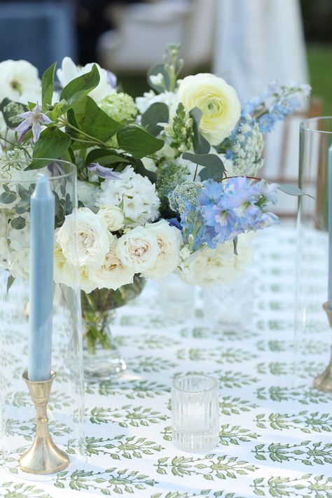 a green and white patterned table linen. the floral arrangement has white and blue flowers with greenery. Green And Blue Tablescape, Patterned Napkins Wedding, Green Wedding Linens, Blue And White Tablescapes Wedding, Blue Table Linens Wedding, Blue Green And White Wedding, White Green And Blue Wedding, Wedding With Blue Accents, Blue Green Wedding Colors