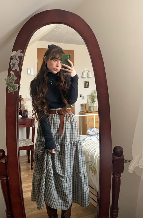 Girl with long wavy brown hair and a bow takes mirror selfie in vintage oval wooden mirror. She is wearing a three tiered dark green plaid maxi skirt with a brown buckle belt and a black long sleeve turtleneck and brown combat boots Architecture Outfit Style, Take Ivy Style Book, Cute Cottagecore Outfits Winter, Easter Vigil Outfit, Fall Outfit Jean Skirt, Winter Outfit Cottagecore, Cottage Core Womens Fashion, Style Long Skirt Winter, Cottagecore Outfits Work