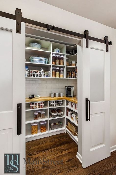 A large walk-in pantry sits behind a modern rolling barn door. It includes plenty of custom open shelving and a functional butcher block countertop. Walk In Pantry Ideas Layout, Walk In Pantry Ideas, Barn Door Pantry, Pantry Layout, Open Pantry, Dream Pantry, House Pantry, Modern Pantry, Cabinet Pantry