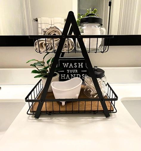 "This multi-purpose, Farmhouse-style countertop organizer is an attractive decorative accent and an effective organizer for the bathroom or any room of the house! This best-seller has more than 75, 5-star reviews!  The rustic Two-Tier Decorative Basket will elevate your bathroom counter however you style it. Check out the reviews for inspiration from our customers who love to fill it with rolled towels, filled jars, cosmetics, lotions, candles, small plants and decorative signs.  DETAILS Dimensi Farmhouse Bathroom Vanity Decor, Towel Organizer Bathroom, Small Bathroom Ideas For Apartments, Airbnb Towel Storage, Above Toilet Towel Storage, Small Bathroom Counter Decor Ideas, Master Bath Vanity Decor, Brown And Black Bathroom Ideas, Bathroom Basket Decor