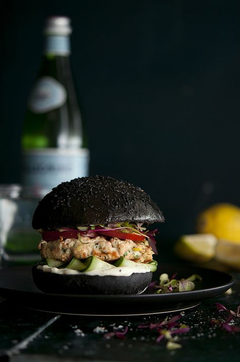 Squid Ink Sal­mon Burger       When I was in Lis­bon this year I tasted the most amaz­ing thing: a squid ink sal­mon bur­ger. Not only did it look freakin’ cool it tasted even bet­ter. The squid ink is subtle, yet com­pletely notice­able and integ­ral. The fla­vour, which I can only describe as being “the sea’ or hav­ing a ‘seaness’ trans­forms a simple sal­mon bur­ger into a fant­ast­ical delight – there really is some­thing quite fun in eat­ing a black burger.     The squid ink com­pli­me... Black Burger, Unique Burgers, Salmon Burger, Salmon Patties Recipe, Black Food, Burger Buns, Wrap Sandwiches, Burger Recipes, Beautiful Food