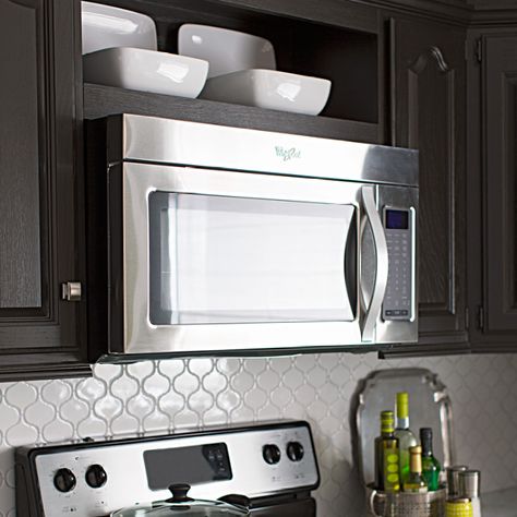 Create new space in your kitchen. Free up counter space by swapping your countertop microwave for an over-the-range model. Then turn a slice of cabinet space above the microwave into an attractive display shelf. Microwave Shelf Over Stove, Microwave Above Stove, Behind Stove Backsplash, Kitchen With Open Shelving, Space Above Kitchen Cabinets, Stove Decor, Microwave Storage, Hgtv Kitchens, Microwave Cabinet