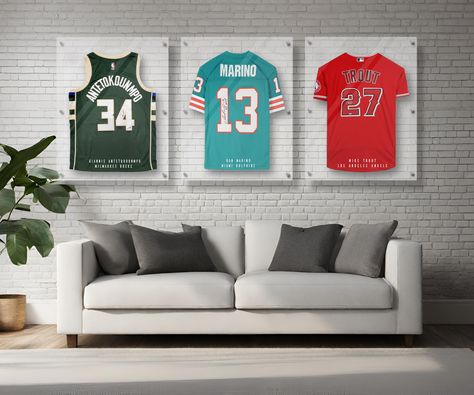 Protect your prized sports jersey with this custom personalized handmade acrylic display frame case. Each storage frame is handmade with 3 panels of ultra-clear 4mm thick high-grade acrylic that is UV-protecting and clear as glass. Each case is made up of 3 stacked acrylic panels. The center panel has a built-in hanger and provides the open spacing for the jersey to be protected from dust. The panels are stacked and locked in place with a series of 6 metal standoffs which then secure easily to y Framed Sports Jersey, Framing A Jersey, Framed Basketball Jersey, Framing Jerseys Diy, Jersey Frame Ideas Display Case, Diy Jersey Display Case, Sport Memorabilia Display Wall, Basement Sports Decor, Framed Jersey Ideas