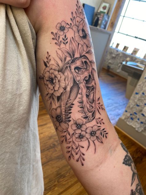 Dinosaur tattoo. Bicep tattoo placement Dinosaur Tattoo For Son, Dinosaur Sleeve Tattoo, Feminine Dinosaur Tattoo, Women Dinosaur Tattoo, Dinosaur And Flower Tattoo, Dino Skull Tattoo, Dino Flower Tattoo, Dino Skull With Flowers Tattoo, Dinosaur With Flowers Tattoo