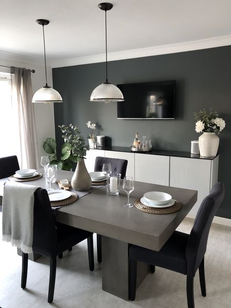 This solid concrete dining table still manages to look elegant in this sophisticated dining room, featuring dark walls and faux foliage, with industrial style pendant lights. The industrial touches are perfectly balanced with the more natural touches such as the curtains and blanket details. Concrete Table Decor, Dining Room Feature Wall, Grey Dining Tables, Concrete Dining Table, Grey Dining Room, Dinning Room Design, Stone Dining Table, Small Kitchens, Concrete Table