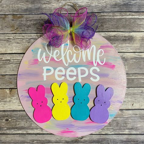 "This fun door sign was inspired by a very popular Easter Candy! This sign is a 15\" round sign hand painted with hints of blue, purple, yellow, and pink. It has 4 painted Wooden Peep bunnies and says Welcome Peeps. It is accented with a fun multi color bow. The door hanger has been sealed to protect it from the elements." Peeps Door Hanger, Peep Door Hanger, Purple Door Hanger, Diy Dollar Store Easter Crafts, Diy Peeps Decor, Easter Peeps Crafts, Easter Paintings For Kids, Every Bunny Welcome Sign, Easter Peeps Decorations