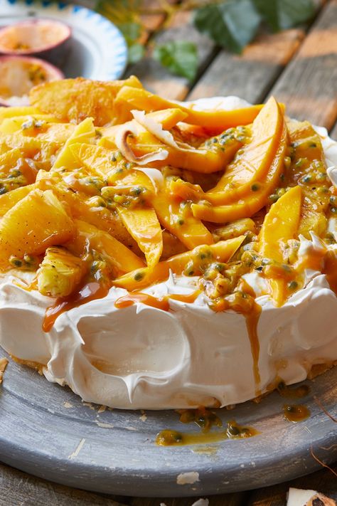 A pavlova base topped with mango slices, passion fruit seeds, roasted pineapple pieces and toffee sauce Tropical Fruit Pavlova, Mango Pineapple Dessert, Mango Pavlova Recipe, Pavlova Food Photography, Summer Pudding Recipe, Pavlova Tropical, Tropical Pavlova, Passion Fruit Pudding, Mango Pavlova