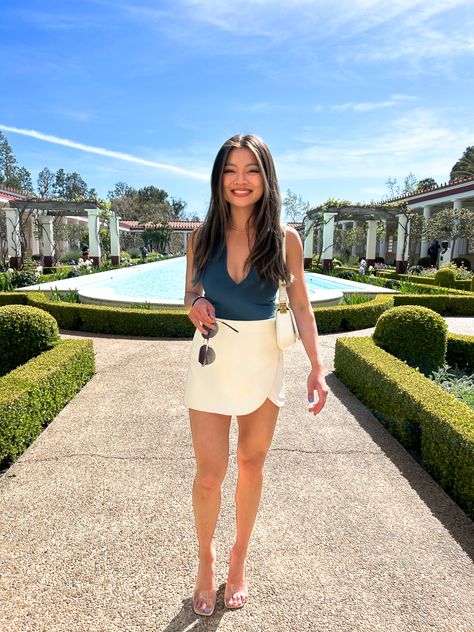 Girl wearing white skirt and teal bodysuit at Getty Villa Skorts Skirts Outfit Ideas, Deep V Bodysuit Outfit, Zara Bodysuit Outfit, Zara Skort Outfit, Skort Outfit Elegant, Nude Bodysuit Outfit, White Skort Outfit, Clear Heels Outfit, Outif Ideas