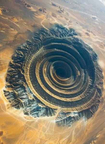 Richat Structure, the "Eye of the Sahara" The Richat Structure, also known as the "Eye of the Sahara," is a prominent circular geological formation located in the Sahara Desert in Mauritania. This distinctive feature, visible from space, resembles a large bull's-eye and is about 40 kilometers (25 miles) in diameter. Initially thought to be an impact crater, it is now believed to be a highly eroded dome of sedimentary rock. The concentric rings of the Richat Structure make it a fascinating su... Eye Of The Sahara, Impact Crater, The Sahara Desert, David Attenborough, Sedimentary Rocks, Sahara Desert, Rock Formations, Landscape Photos, Nature Travel