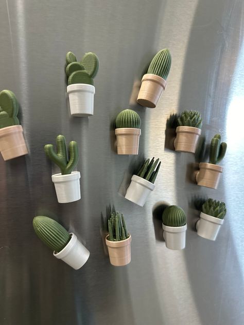 Bring a touch of whimsical desert charm to your kitchen with our 3D printed cactus refrigerator magnets! Each decorative magnet in the Charming Cacti Collection is meticulously crafted to replicate the delightful intricacies of various cactus species, making them unique fridge magnets. Details: 🌵Set of 6 Unique Cactus Designs 🌵Each magnet varies in size, approximately 2" tall. 🌵3 Color Pots to choose from (muted white, white marble, wood grain)  🌵Made with high-quality PLA plastic 🌵Magnet ideal for holding notes on your fridge, filing cabinets, or any magnetic surface. How to Order: 1. Select color pot wanted 2. Add to cart You may also like: https://wiocreationsllc.etsy.com/listing/1161303293 https://wiocreationsllc.etsy.com/listing/1042013430 Shipping: 📫 Ships in 1-5 business days Polymer Clay Kitchen Decor, Cactus House Decor, Clay Kitchen Magnets, 3d Printed Fridge Magnets, Airdryclay Magnet Ideas, 3d Printed Magnets, Unique 3d Printing Ideas, 3d Printed Gift Ideas, Air Dry Magnets