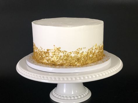 Watch this video to see how you too can make this elelgant white and gold cake! White Cake Gold Flakes, White And Gold Birthday Cake For Men, Simple Wedding Cake White And Gold, White Cake Gold Sprinkles, Gold Fleck Cake, Gold White Cake Birthday, White And Gold 40th Birthday Cake, White Cake With Gold Accents, White Gold Cake Design