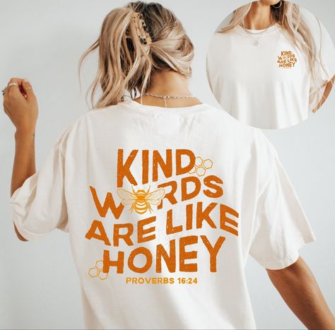 "Kind Words Are Like Honey", design on chest, doodle graphic adorns back side. Brand: Comfort Color T-Shirt, Gildan Crewneck Sweater Color: Ivory T-shirt, White Crewneck  >> If you would like to customize on a different color/style garment, please message me and we can create together :) Size up one or two sizes for an oversized fit.  --- --- --- --- --- --- --- --- --- --- --- WASHING INSTRUCTIONS --- --- --- --- --- --- --- --- --- --- --- For best results, wash on cold/delicate cycle, hang dry, do not iron directly onto design, do not dry clean. No fabric softener. SHOP ANNOUNCEMENTS --- --- --- --- --- --- --- --- --- --- I regularly update my turnaround timeframe. These timeframes can be found in the "Shop Announcement" section. However, please keep in mind once the packages are dropp Easy Shirt Designs, Cute Shirt Ideas, Christian Tshirt Design Ideas, Kind Words Are Like Honey, Words Are Like Honey, Christian Clothes, Christian Tee Shirts, Christian Graphic Tees, Christian Tshirt Design