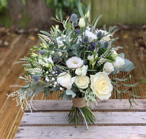 Wedding bouquet of eucalyptus, white roses and blue thistle with hessian ribbon Wedding Flowers With Blue Thistle, Fresh Flowers Wedding Bouquet, Bouquets With Thistle, Rosemary And Eucalyptus Wedding, Hydrangea And Thistle Bouquet, Bridal Bouquet Eucalyptus White, White And Thistle Wedding Flowers, Wedding Bouquets With Thistles, Thistle Wedding Centerpieces