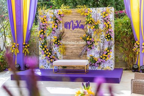 Charming purple with yellow and white backdrop by Red Velvet Events-Dubai. #mehendi #mehendidecor #mehendiseating #indianwedding #wedding #weddingdecor #indiandecor #southindianwedding #haldidecor #hindubride #teluguwedding #tamilwedding Engagement Arrangements Ideas, Wedding Backdrop Ideas Diy, Haldi Photo Booth, Engagement Arrangements, Backdrop Ideas Diy, Flower Wedding Backdrop, Wedding Backdrop Ideas, Lilac Decor, Haldi Decoration Ideas