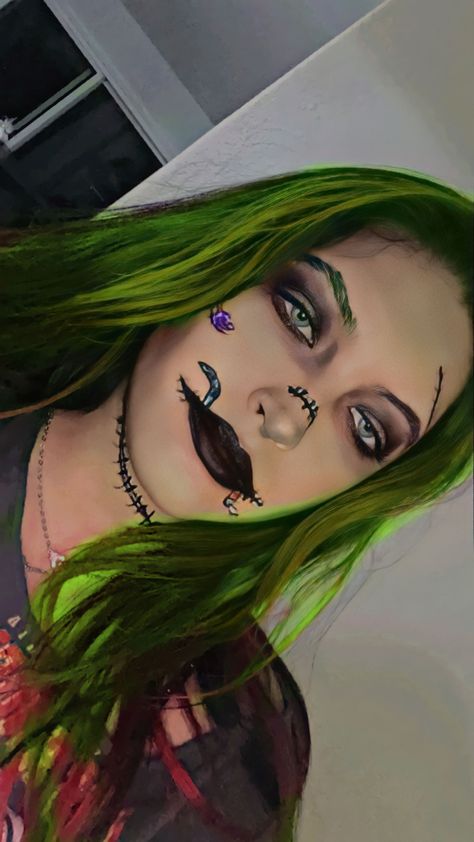 Girl with long green hair and makeup stitches on face and makeup drawn colorful worms coming out from the sides and stitched up black lips with one green eyebrow and a purple spider on her cheek makeup look inspired from the character in Nightmare Before Christmas named Oogie Boogie Oogie Boogie Inspired Makeup, Oogie Boogie Halloween Makeup, Oggie Boogie Make Up, Ophir Boogie Makeup, Boogie Man Makeup, Oogie Boogie Eye Makeup, How To Draw Oogie Boogie Step By Step, Oogie Boogie Disfraz, Oogie Boogie Makeup Ideas