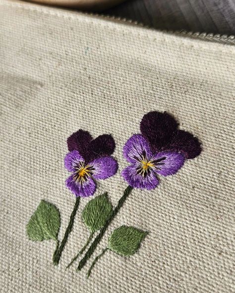 Earlier in the week, I posted a reel asking for help with what flower I should stitch on a zipper pouch that I had. The top responses were the Flax and the Pansies, so I stitched both! I'm really pleased with how these came out. My purple pansies are so detailed that even I surprised myself, lol. Both pouches are available in my Etsy shop! Thank you for your help in deciding, although I think I may need to get more pouches so I can stitch up the other designs! . . . . . . . . . . . #mi... Pansy Embroidery, Embroidery Simple, Purple Pansies, Asking For Help, Purple Pansy, Ask For Help, Pansies, Zipper Pouch, No Response