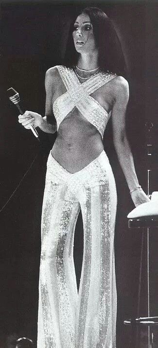 Cher, 1970s. White and sequin bell bottom pants with a criss cross top. Cher 70s, 1970s Outfits, 70s Mode, 70s Jumpsuit, Cher Outfits, Fashion 70s, Gene Kelly, Mae West, 70s Disco