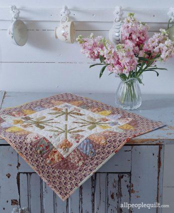 Soft pastel florals and olive green and lavender prints welcome spring in the simple appliqué quilt. Pinwheel Block, Table Topper Patterns, Creeper Minecraft, Mini Quilt Patterns, Spring Quilts, Winter Table, Flower Motifs, Miniature Quilts, Embroidered Quilts