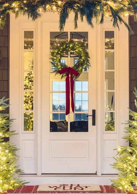 white front door with wreath with twinkle lights and red bow Light Up Christmas Wreaths, Christmas Window Wreaths, Front Door With Wreath, Exterior Christmas Decor, Front Porch Christmas Decorations, White Tree Decorations Decorating Ideas, Front Planters, White Tree Decorations, Exterior Christmas Decorations