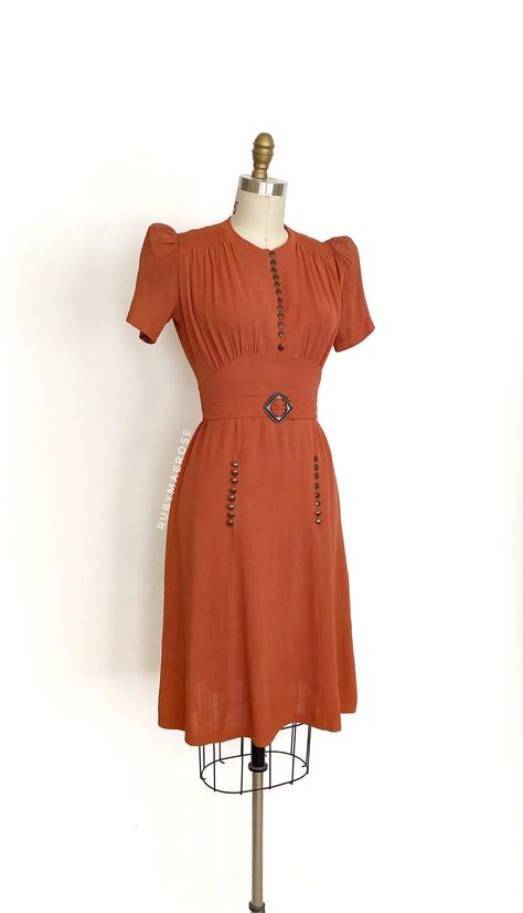 "vintage dress  Era: 1930's Label: none Closure: side metal zipper Material: rayon Colour: cinnamon burnt orangish brown  Details: all the timeless 30's construction details, puff short sleeves with small shoulder pads, decorative skirt buttons, original matching waist belt with buckle Fits like: xsmall / small Bust: 32 - 36\" Waist: 24/25\" Hips: 34 - 36\" Length: 39.5\" Condition: An as is, as found beauty. There is still a vintage smell even after washing it. The buttons are modern but a good match with the vintage buckle. There are inconsistencies in the colour throughout the dress. There are spots and marks on the skirt. Some ares of discolouration at the waist and on the back of the bodice. There are some tiny holes at the back shoulder area.  Priced accordingly.   shop policy  * All Vintage Reproduction Clothing, 1940s Shirtwaist Dress, 1930s Womens Fashion, 1930s Day Dress, 30s Outfits, 1930s Outfits, 1930 Dress, 1930s Fashion Women, 40s Outfits