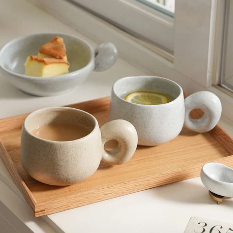 Funky and organic looking ceramic glazed mugs not only add retro decor to your home, but they create cozy moments out of the simplicity of drinking your favorite beverages. The handcrafted nature, glazing, and kiln processes preformed on the pottery ensures each cup has its own character with exaggerated handle design—adding to their natural appearance and organic retro style. Available in two different earthy colors and organic shapes offering two options of shallow and deep sizes for sipping, Japanese Stoneware, Cute Coffee Cups, Beige Ceramic, Retro Coffee, Neutral Aesthetic, Tableware Design, Modern Japanese, Nordic Home, Stoneware Mugs