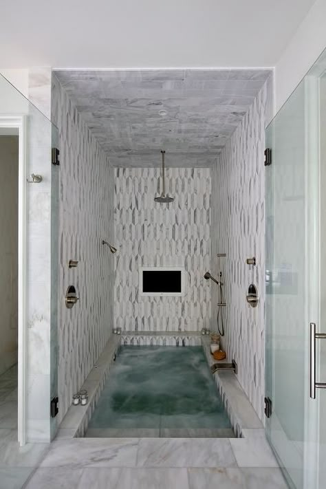 Stunning spa shower boasts white and gray marble tiles and ceiling fitted with a built in TV and a circular rain shower head and sprayer aimed over a sunken bathtub with steps leading out through double glass doors to white marble floors. Spa Room Ideas, Sunken Bathtub, Sunken Tub, White Marble Floor, Spa Rooms, Spa Shower, Bad Inspiration, Bathroom Tub, Tub Shower Combo