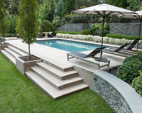 The Essentials to Consider Before Building a Pool - The Scout Guide Steps Up To Pool Area, Step Down To Pool Area, Pool On Sloped Yard Retaining Walls, Terraced Pool Landscaping, Patio With Steps Down From House To Pool, Retaining Wall Ideas Hillside Pool, Swimming Pool Sloped Backyard, Small Backyard With Pools, Traditional Pool Design