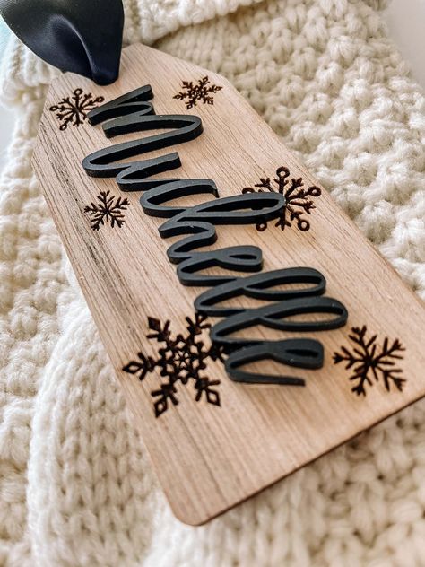 "- Personalized Wooden Stocking Name Tag -  This stocking tag is beautiful, chic and the perfect addition to your Christmas stocking.   This stocking tag is made of 1/8\" birch and measures 2.5\" wide x 5.5\" long.  A beautiful 1.5\" wide satin ribbon has been added for easy hanging and fray check has been added to prevent fraying.    The name has been laser cut and is made of 1/8\" acrylic.  The background of the tag has snowflakes that have been laser engraved into the wood." Laser Made Gifts, Wooden Laser Crafts, Easy Glowforge Projects, Holiday Laser Projects, Christmas Stocking Name Tag Ideas, Cricut Christmas Stockings, Laser Cnc Projects, Elf On The Shelf Laser Cut Ideas, Fall Laser Engraving Ideas