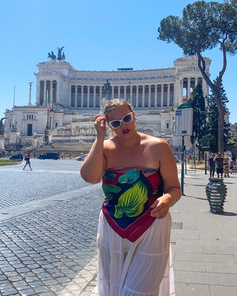 A woman stands in front of the piazza venezia in Rome. The Caucasian woman has her brown hair pulled, she is wearing white cat eye sunglasses and red lipstick. She is wearing a silk scarf as a top and a long float white skirt. Scarf Top For Plus Size, Italy Vacation Outfits Plus Size, European Summer Plus Size, Plus Size Scarf Top, Europe Outfits Plus Size, Italy Outfits Summer Midsize, Midsize Europe Outfits, European Summer Outfits Curvy, Spring 2024 Fashion Trends Plus Size