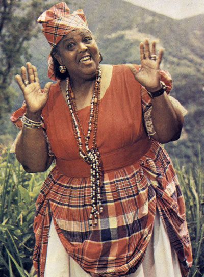 Jamaica's folk ambassador Miss Lou Miss Lou in The National Costume on the cover of her book Jamaica Labrish. A full-flaired skirt made of Madras bandana (predominantly red plaid cotton) material worn usually with a white blouse edged with matching bandana. Headwear varies from bandana wrapped in a special design to straw hat decorated with flowers. Jamaica Culture, Jamaica History, Jamaican People, Jamaican Women, Jamaican Culture, Caribbean Culture, Black Culture, Bob Marley, Black People