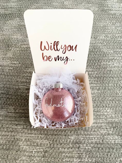 "Godmother proposal gift box is the perfect gift and such a special way to ask.  Will you be my godmother?  *Product Details* 3.25\" Plastic Disc Shape Ornament (M&M shape) Glitter is fully sealed inside ornament (Rose Gold Glitter) Design is made with permanent and high quality vinyl (White is pictured)  Box will include: (1) Plastic Ornament  (1) White Gift Box   (1) Crinkle white paper No other items are included.   Wording on gift box will come as shown with \"Will you be my...\" in Rose Gold lettering.        Return Policy No returns or exchanges due to custom and made to order.  But please contact me if you have any problems with your order." Godmother Box Proposal Ideas, Will You Be Godmother, Asking Friend To Be Godmother, Godmother Ornament, Godmother Christmas Gifts, Do You Want To Be My Godmother Ideas, Godmother Proposal, Would You Be My Godmother Ideas, Asking Godmother Ideas