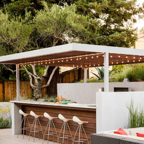 Outdoor bar:  Elaine Barden envisioned her backyard retreat as “Palm Springs meets W Hotel style.” Her designers chose a custom fabricated aluminum arbor above an outdoor bar. The team built it on-site and painted it silver to match the wall sconces. Redwood slats cover the top. Patio Bars, Modern Outdoor Kitchen, Hillside Garden, Outdoor Kitchen Bars, Outdoor Dining Room, Door Kitchen, Backyard Bar, Backyard Kitchen, Kitchen Outdoor