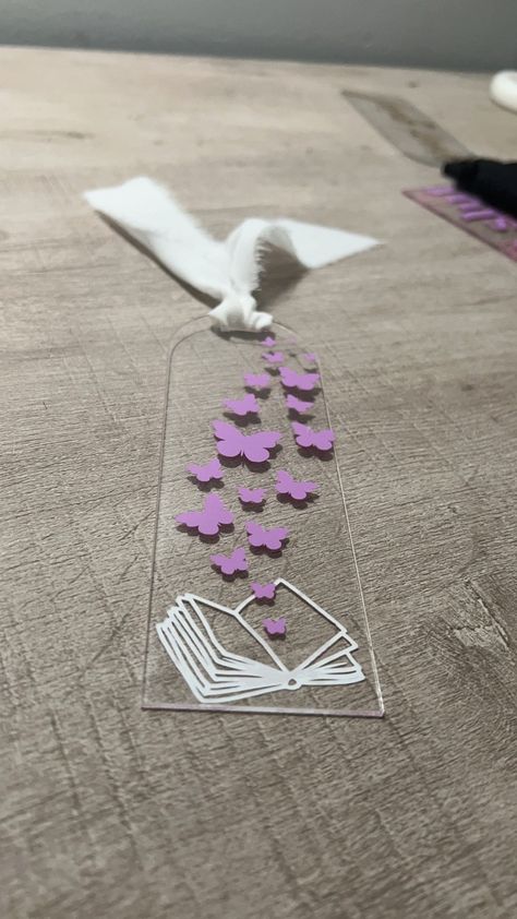 butterflies flying from the pages book mark.  2in by 6in clear acrylic bookmark with chiffon ribbon tassel and double sided white and purple vinyl design Diy Acrylic Bookmarks Cricut, Bookmark Vinyl, Acrylic Bookmarks Cricut, Vinyl Bookmarks, Bookmarks Cricut, Acrylic Bookmark Ideas, Cricut Bookmarks, Acrylic Bookmarks, Diy Vinyl Projects