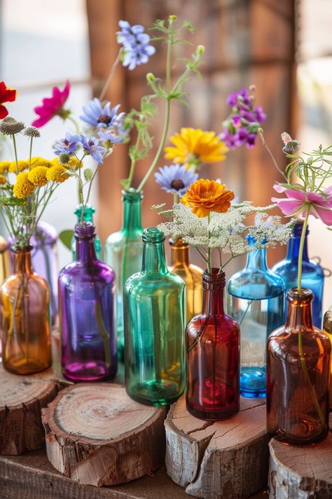 Capture the essence of bohemian elegance on your special day 🌸. These simple yet stunning wedding table centerpieces combine rustic wood slices and vibrant glass bottles for a unique touch. Perfect for couples who love a pop of color and natural beauty in their decor. #BohoWedding #WeddingInspiration #CenterpieceIdeas #WeddingDecor #DIYWedding #RusticChic #FloralDecor #WeddingDetails Recycled Bottles Wedding Decor, Colourful Boho Wedding Decor, Boho Colorful Wedding Decorations, Wedding Bohemian Decorations, Indoor Wildflower Wedding, Thrifted Glass Wedding Centerpieces, Indie Wedding Decor, Vibrant Wedding Centerpieces, Diy Eclectic Wedding Decor