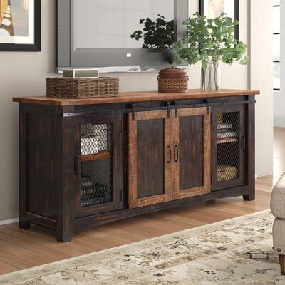 This solid wood TV stand brings rustic farmhouse charm to your living room or family room. Two (2) sliding barn-style doors glide smoothly on a sleek black metal track, allowing easy access to the center cabinet. Metal mesh-style side doors add a modern industrial twist, creating a perfect fusion of classic and contemporary aesthetics. Four (4) removable and adjustable interior shelves provide storage space for your audio, video, and gaming components. Cable management cutouts are conveniently p Tv Stand Wayfair, Rustic Tv Stand, Stands Tv, Barn Style Doors, Wood Tv Stand, Solid Wood Tv Stand, Into The Wood, Tv Stand With Storage, Cool Tv Stands