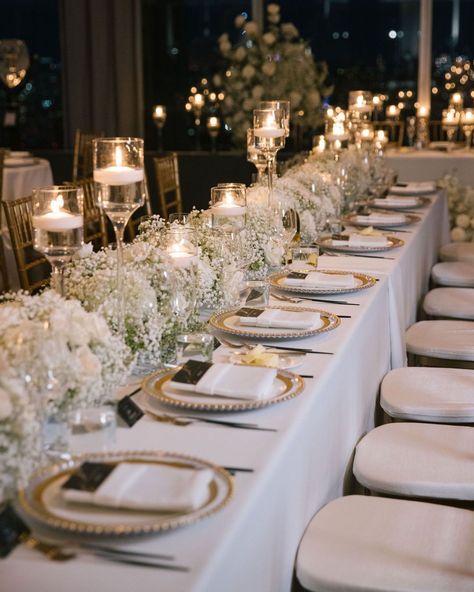 Transform your reception into a regal affair with intricate gold tablescape details. White florals, statement candles and the gold accents create an ambiance of opulent elegance. ✨   #weddingtablescape #tabelscapedesign #weddingreception #weddinginspo #weddingdetails #weddingdecor #weddingstyle #weddingplanner #nycweddings #overthemoon #stylemepretty #luxuryweddings #caratsandcake #alinatoevents Reception Table Decorations Candles, Elegant Outdoor Wedding Reception Table Arrangements, White And Gold Wedding Place Setting, White Wedding Design, Timeless Wedding Tablescape, Classic Elegant Wedding Table Setting, Wedding Themes White And Gold, Neutral Wedding Decorations Receptions, White Floral Wedding Table Decor