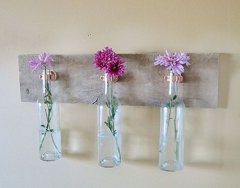 Bring your garden inside by placing flowers into a hanging wine bottle display. Wine Bottle Craft, Wine Bottle Project, Wine Bottle Display, Wine Bottle Wall, Wine Bottle Vases, Bottle Projects, Wine Bottle Ideas, Wine Crafts, Old Wine Bottles