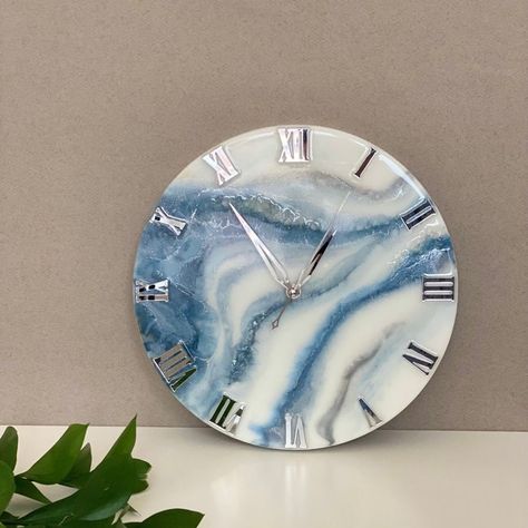 This mesmerizing resin clock inspires creativity within you. Put it up in your living room or your room; this resin charm will never fail to please you with its awestruck beauty. It makes your wall simple, yet stylish.  * Can be a good gifting option for interior decoration.  * Designed by specially trained artist for one time only. Thus, this art cannot be copied. It's not just a clock, it's a time piece.  * They are made from mixed media including wood, fabrics, gold leaf, feathers, sand, shells and other creative materials.  * The artwork is then preserved under several coats of quality resin.  * They are fitted with a quality Quartz movement making it an accurate and beautiful timepiece. - Made from Premium Resin. - Comes in an attractive colours that elevates the look of the home/ off Diy Resin Gifts, Epoxy Resin Wall, Resin Gifts, Resin Wall Clock, Resin Clock, Diy Resin, Resin Charms, Resin Diy, Interior Decoration