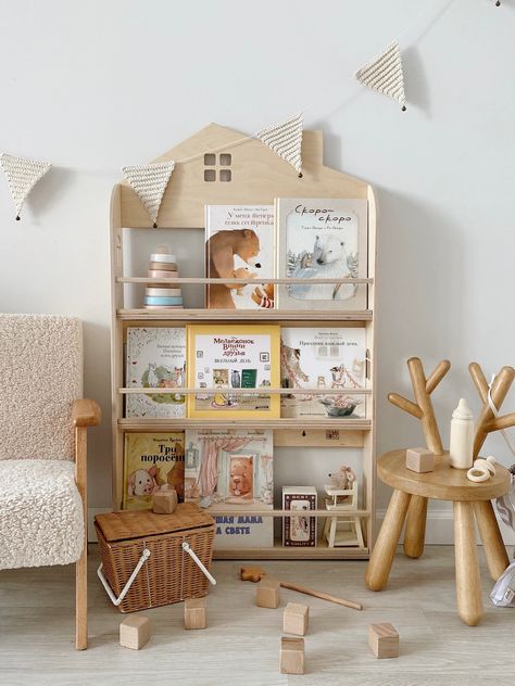 An original wall shelf for books in the shape of a house. Holds up to 50 books of medium thickness and different formats. Stoppers at the top and bottom prevent books from falling out. The top shelf is for the tallest books, the middle one is for small ones, and the bottom one is for A4 format. Height 106 cm, depth 10 cm, width 60 cm. With such a shelf, the child can easily find his favorite book and be able to get it out on his own. According to child psychologists, display book storaging is th Storage In Nursery, Bookshelf House, Montessori Bookcase, Childrens Shelves, Display Bookshelf, Montessori Bookshelf, Colorful Playroom, Modern Dollhouse Furniture, Nursery Bookshelf