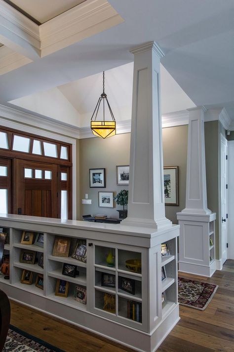 This creative storage space was designed by TriplePoint Design Build to accommodate books and living room knickknacks in the entryway of this remodeled home. The bookcases and columns, which were painted white to match to ceiling and trim of the home, divide the foyer from the living room. The size of the cubby space mirrors the sidelight cutouts above the front door for an interesting effect. Craftsman Modern Interior, Stunning Entryways, Modern Craftsman Interior Design, Modern Craftsman Interior, Interior Pillars, Craftsman Interior Design, Unfinished Kitchen Cabinets, Beautiful Bedroom Designs, Craftsman Interior