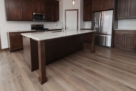 Beautiful wood-look luxury vinyl plank in white kitchen with dark wood cabinets and quartz counter top. Flooring With Dark Cabinets Kitchen, Luxury Vinyl Plank Flooring Kitchen, White Kitchen With Dark Wood, Light Floors Dark Cabinets, Medium Brown Kitchen Cabinets, Vinyl Plank Flooring Kitchen, Kitchen With Dark Wood Cabinets, Dark Wood Kitchen Cabinets, Dark Brown Cabinets