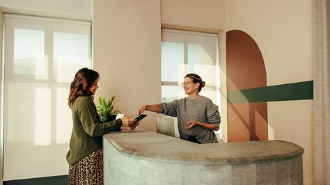 Carefree receptionist assisting a woman with signing in to an office Office Receptionist, Modern Lobby, Shot List, Photo Reference, Kiosk, Check In, Lobby, A Woman, Ipad