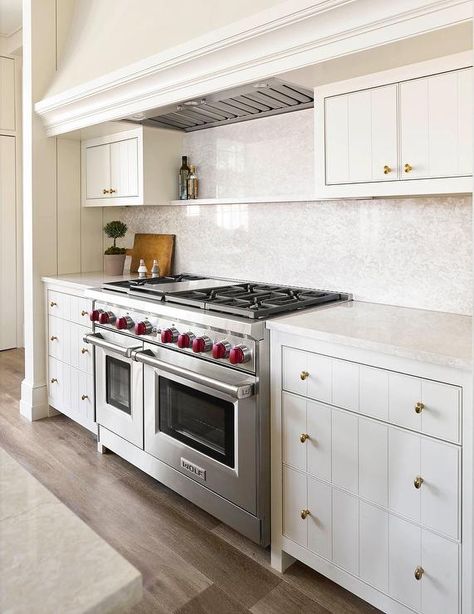 An off-white kitchen hood stands over a marble spice shelf, flanked by small cabinets, and a Wolf dual range. Ashley Montgomery, White Kitchen Hood, Off White Kitchen Cabinets, Cream Kitchen Cabinets, Off White Kitchens, Shiplap Backsplash, Spice Shelf, Vintage Stoves, Kitchen Hoods