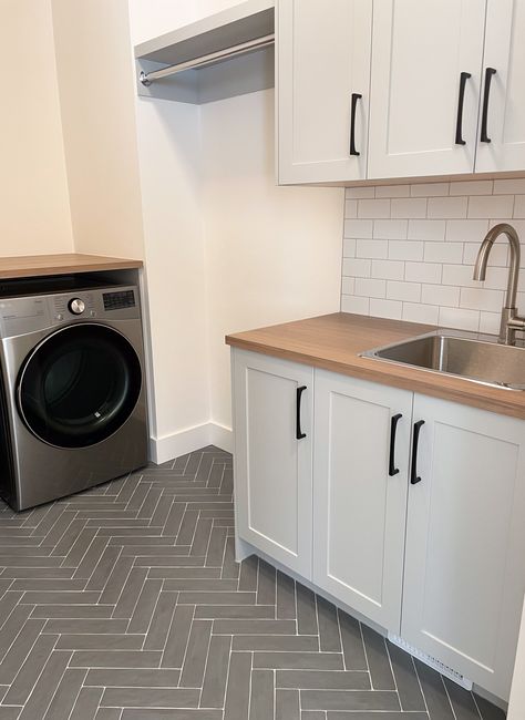 Best features of this new laundry room? It's hard to pick only a few, but the hanging bar, herringbone tile floor and large sink are at the top. What are your laundry room must-haves? Weigh in and check out more pics of this space! Small Laundry Room Ideas With Hanging Space, Laundry Room With Hanging Space, Grey Tile Laundry Room, Laundry Room Hanging Bar, Laundry Room Flooring Ideas, Studio Mcgee Laundry Room, Mcgee Laundry Room, Laundry Flooring, Laundry Room Must Haves