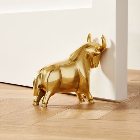 Decorative gold door stopper holds steady-no bull. Press flat side with horns up against the door for full support; equally sharp as a bookend. CB2 exclusive.  -Aluminum gold tinted body -Iron weight inside -6.6 lbs/2.97 kg -Clean with soft cloth -Made in India Pascal The Bull Gold Doorstop-Bookend. Brass Decorative Objects, Weird Office Decor, Door Toppers Ideas, Book Ends Aesthetic, Farmette Ideas, Door Support, Wooden Home Accessories, Luxury Gadgets, Philadelphia Apartment