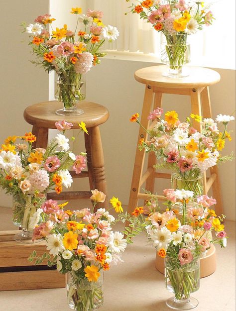 6 vases full of flowers displayed on wooden stools and such. The flowers are white, yellow, and dusty pink with hints of orange. They arranged in a garden style with a  wild whimsical look. Yellow Cosmos, Pink Lisianthus, Yellow Flower Arrangements, Large Vases, Yellow Bouquets, Baby Shower Yellow, Daisy Wedding, Floral Aesthetic, Gerber Daisies