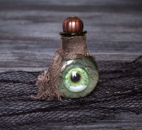 The creepy miniature bottle in dollhouse scale 1:12 is a great eyecatcher for Halloween. The small bottle is made of green glass, and filled with a magical tincture. The front of the bottle is dekorated with a glass pupil. The bottle-neck is adorned with a rag scarf. The bottle is closed with a bronze bead. Measurements: Height: 3.1 cm / 1.22 inch Width: 2 cm / 0.79 inch Depth: 1 cm / 0.39 inch IMPORTANT: The prise is for the bottle only. I added the owls for illustration only. Attention: This a Mini Glass Bottles Ideas, Haunted Dollhouse Diy Ideas, Medicine Bottle Crafts, Scary Halloween Crafts, Decorated Bottles, Dollhouse Halloween, Halloween Potion Bottles, Halloween Apothecary, Haunted Dollhouse