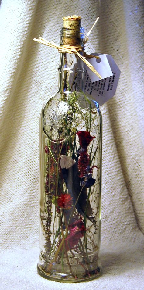 Dried flowers fill this clear wine bottle. Clear Bottle Decor, Clear Wine Bottle Crafts, Wine Bottle With Flowers Inside, Dried Flowers In A Bottle, Dried Flowers In Wine Bottle, Alcohol Bottle Decor, Wine Bottle Vase Flowers, Wine Bottles With Flowers, Flower In Wine Bottle