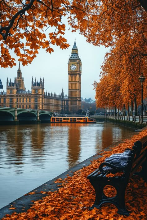 Enjoy a picturesque autumn morning in London with Big Ben rising through a soft golden fog. Vibrant orange leaves drift from trees along the Thames, creating a stunning fall scene. A cozy bench by the riverbank, complete with blankets and warm coffee, invites you to savor the crisp air. Iconic red double-decker buses cross Westminster Bridge, adding to the charm of this serene setting. This image perfectly captures the essence of September and the beauty of autumn in the heart of London. Fall In England, United Kingdom Aesthetic, Autumn England, London Morning, Autumn London, London Images, Kingdom Aesthetic, London Autumn, London Wallpaper